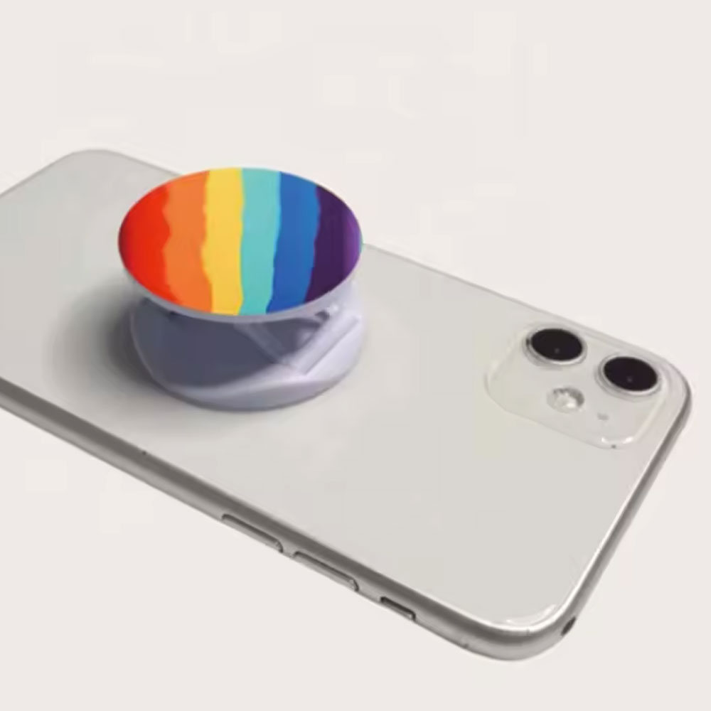 An NFC phone grip with a rainbow top, stuck to the back of a phone.